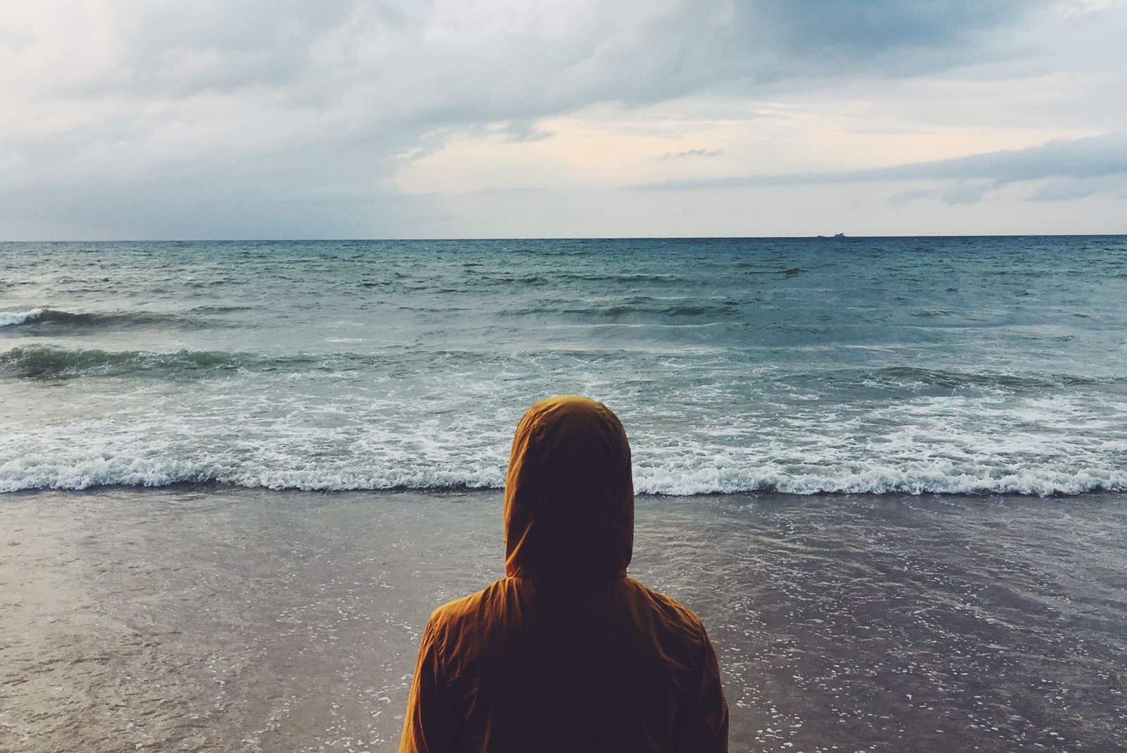 Foto di me che guardo il mare mentre indosso una giacca gialla anti-vento con cappuccio