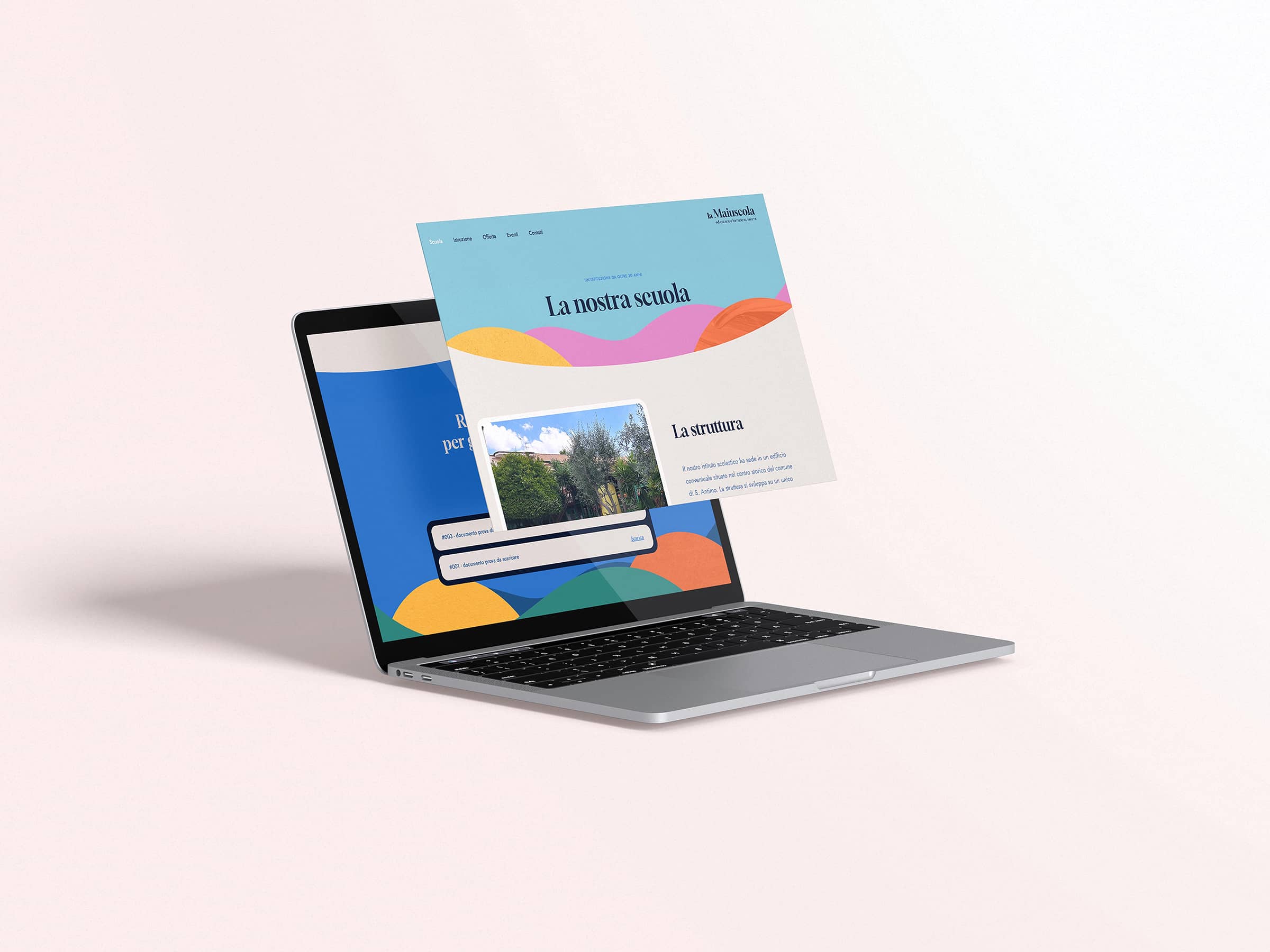 Gray laptop on a light surface displaying colorful sections of a website with Italian text about a school.