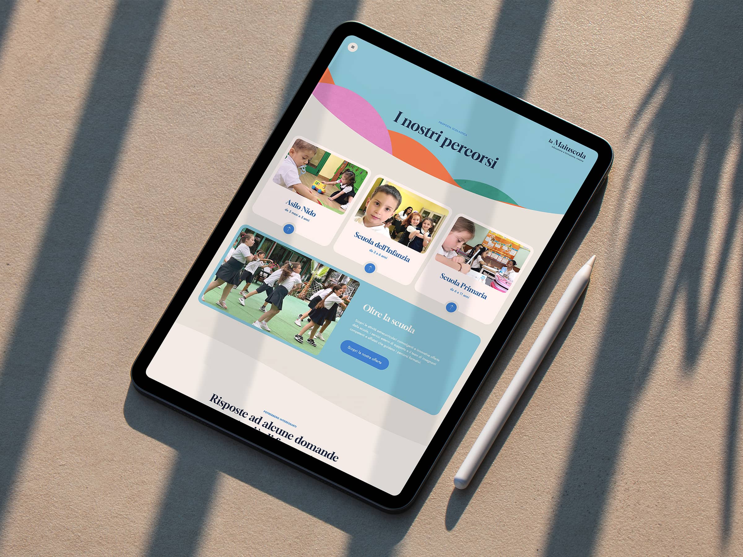 Tablet displaying an educational website in Italian about school paths with images of children in nursery, preschool, and primary school settings, alongside a stylus on a beige surface.